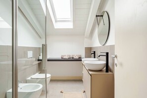 Een moderne badkamer met dakraam, grote spiegel, wit wastafel en een douchetoilet.
