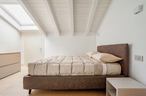 Een slaapkamer met een bed, nachtkastje en dakraam.