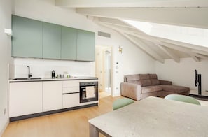 Eine moderne Küche mit weißen Schränken, einem eingebauten Backofen und einem Essbereich mit Tisch und Stühlen.