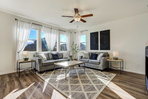 A living room with a sofa set, a coffee table, a patterned rug, and a ceiling fan. - New Spacious and Luxurious Home (Colorado Springs)