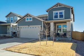 A two-story house with a garage, a small patio with chairs, and a tree in the front yard. - New Spacious and Luxurious Home (Colorado Springs)