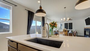 A modern kitchen with a large island, stainless steel appliances, and pendant lighting. - New Spacious and Luxurious Home (Colorado Springs)
