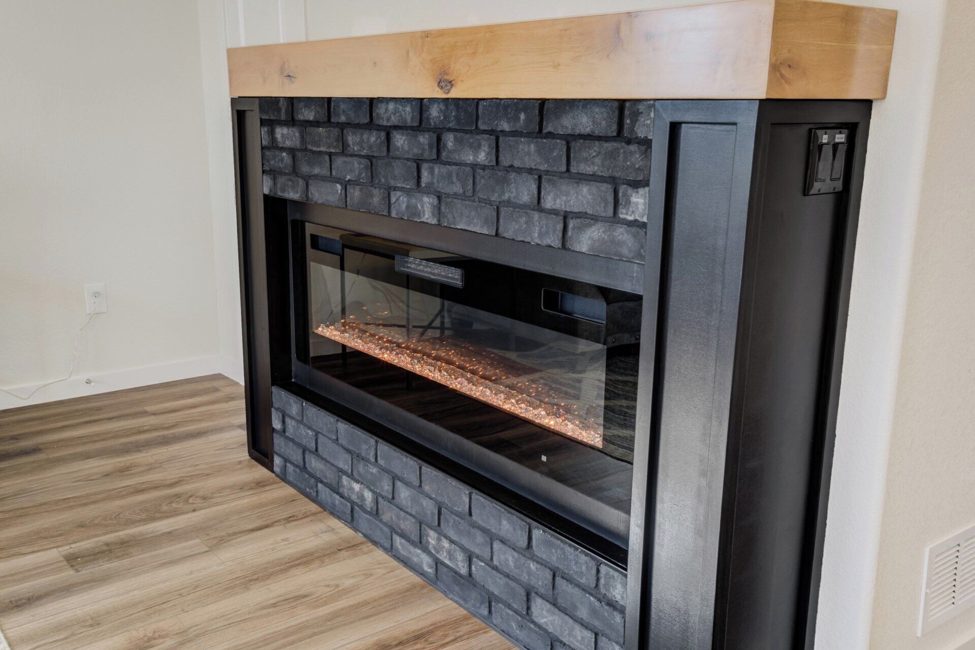 Une cheminée moderne avec une façade en briques et un manteau de cheminée en bois.