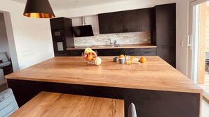 Une cuisine moderne avec un îlot central en bois, des meubles de rangement noirs et un four à micro-ondes encastré.