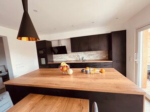 A modern kitchen with a wooden island, black cabinets, and a built-in microwave. - Le Noisetier near EUROPAPARK, RULANTICA (30minutes away) Christmas market in Alsace (Sundhouse)