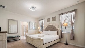 Ein Schlafzimmer mit einem großen Bett, Nachttischen, einer Bank, einem Spiegel und einer Deckenleuchte.