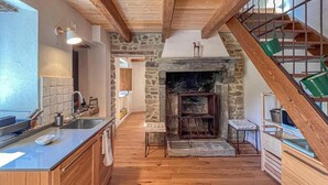A kitchen with a stone fireplace, wooden beams, and a wooden staircase. - Tuscan Organic Farm House Alba Etrusca (cortona)
