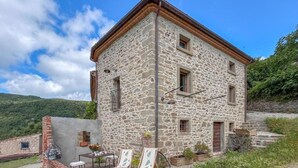 A stone building with a balcony, a table, and chairs. - Tuscan Organic Farm House Alba Etrusca (cortona)