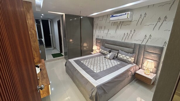 Een moderne slaapkamer met een groot bed, een plafondventilator en een luchtbeheersingssysteem aan de muur.