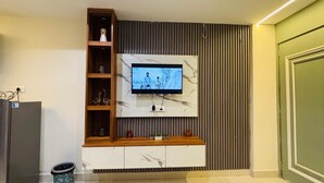 Een moderne woonkamer met een flatscreen televisie bevestigd aan een marmeren muur, houten planken en een inbouwmeubel.