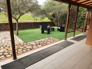 A patio area with artificial grass, stone flooring, and outdoor furniture. - Palau - Sardinia - Italy (Palau)