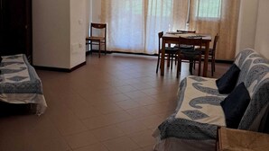 Een kamer met een bed, een bank, een eettafel met stoelen en een raam met gordijnen.
