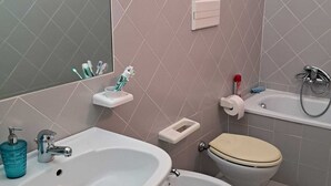 Een badkamer met een wastafel, toilet en spiegel.