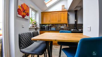 A modern kitchen with wooden cabinets, a tiled backsplash, and a skylight above the dining area.