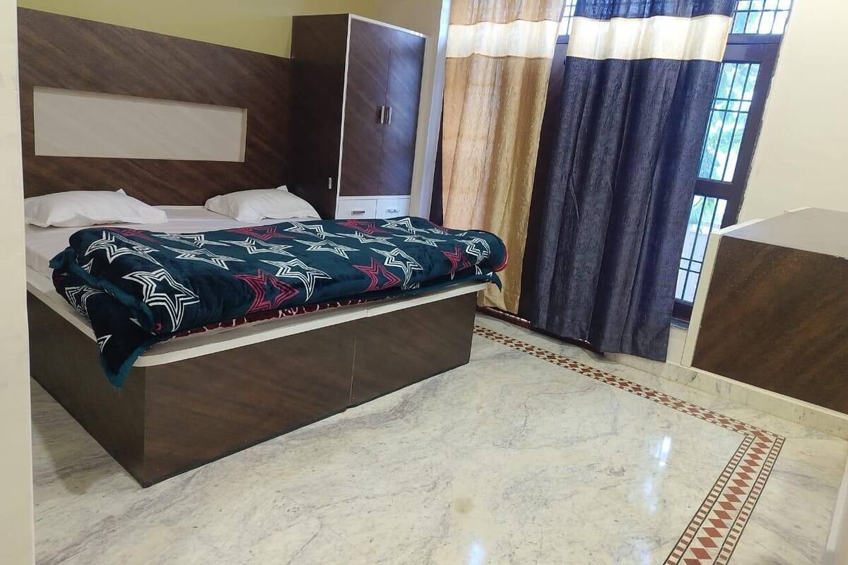 A bedroom with a bed, a wardrobe, and a window with curtains.