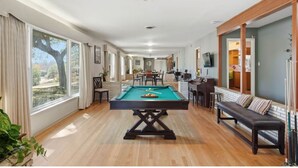 Ein geräumiges Zimmer mit Poolbillard, einer Couch und einem Essbereich.