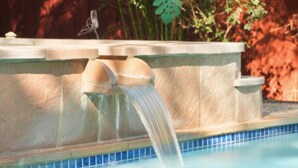 Ein Pool mit einer Steinmauer und einem kleinen Wasserfall.