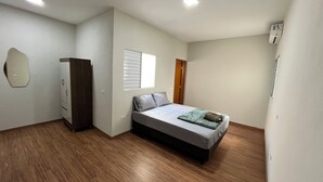 Een slaapkamer met een bed, een kledingkast, een raam en een deur.