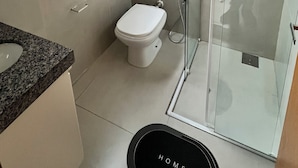 Een badkamer met toilet, douchecabine, wastafel en raam.
