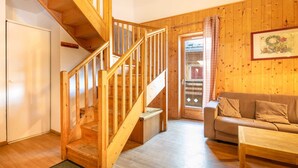 A wooden staircase leading to a loft bedroom, a living room with a sofa and a coffee table, and a wooden wall with a framed picture. - Pet-friendly Family Home With Balcony (Saint-Sorlin-d'Arves)
