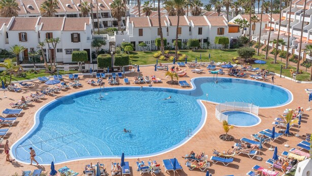 A resort with a large pool, sun loungers, and palm trees. - Vacation Home 'Santiago Beach' with Sea View, Shared Pool and Wi-Fi (Costa Adeje)