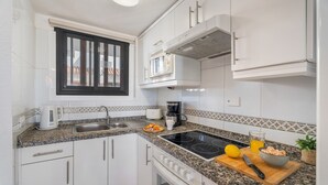 A modern kitchen with white cabinets, a black-framed window, a built-in oven, and a granite countertop. - Vacation Home 'Santiago Beach' with Sea View, Shared Pool and Wi-Fi (Costa Adeje)