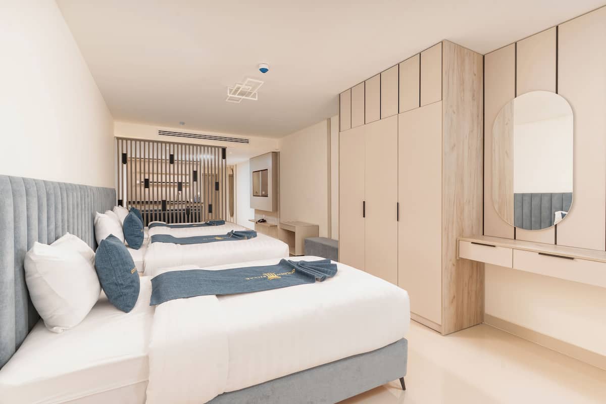 A modern hotel room with a large bed, a vanity with a mirror, and a wardrobe.