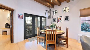 Un comedor con una mesa y sillas de madera, una lámpara colgante y obras de arte en las paredes.