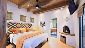 Un dormitorio moderno con una cama grande, una chimenea y vistas al baño.