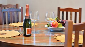 Una mesa de comedor con una botella de vino, dos copas y un cuenco de fruta.