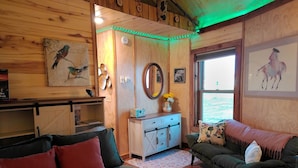 A cozy room with wooden walls, a sofa, a couch, and a small cabinet. - Grain Bin Studio Suite: Unique Stay in the SLV (Moffat)
