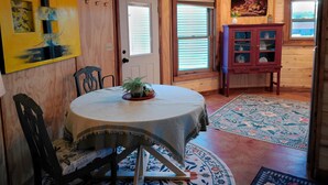 A cozy dining area with a round table, chairs, and a cabinet with glass doors. - Grain Bin Studio Suite: Unique Stay in the SLV (Moffat)