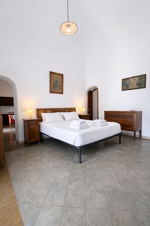 A bedroom with a bed, bedside tables, a dresser, a hanging light fixture, and two paintings on the walls. - Casa Lucia  (Positano)