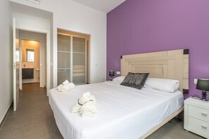 Ein Hotelzimmer mit Bett, Nachttisch, Lampe, Kleiderschrank und einem durch eine offene Tür einsehbaren Badezimmer.
