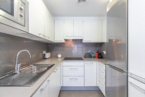 Eine moderne Küche mit weißen Schränken, Edelstahlgeräten und einer eingebauten Spüle.