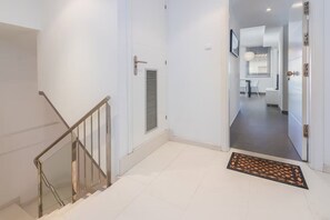 Ein heller, moderner Flur mit Treppe, einer Tür zu einem anderen Raum und einer Fußmatte.