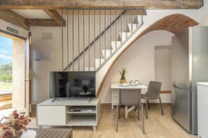 Ein moderner Wohnraum mit Fernseher, Essbereich und Treppe.