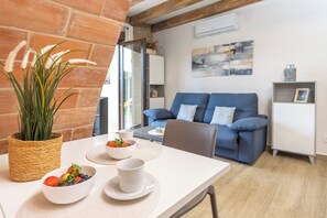A dining area with a table set for two, a blue sofa, and a wicker plant.