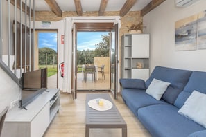 A modern living room with a sofa, a coffee table, a TV, and a door leading to an outdoor area.