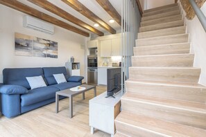 A modern living room with a sofa, coffee table, TV, and staircase.