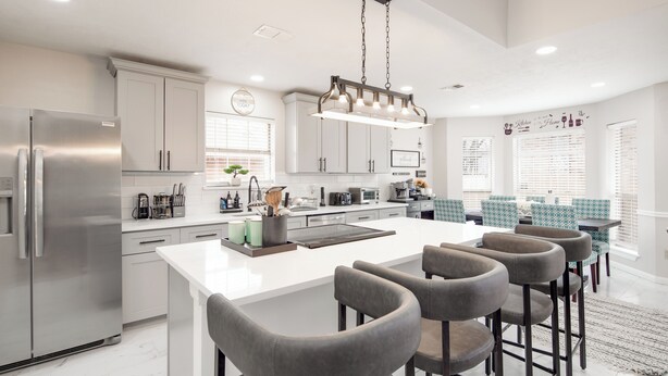 A modern kitchen with a large island, bar stools, and stainless steel appliances. - Gig ‘Em Ags! Pool table, patio, 7 mins Kyle Field (Bryan)