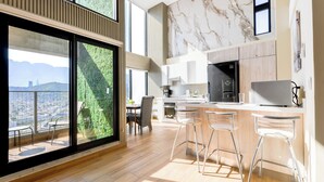 Une cuisine moderne dotée d’un grand îlot central, de tabourets de bar et offrant une vue sur le paysage urbain grâce à de grandes fenêtres.