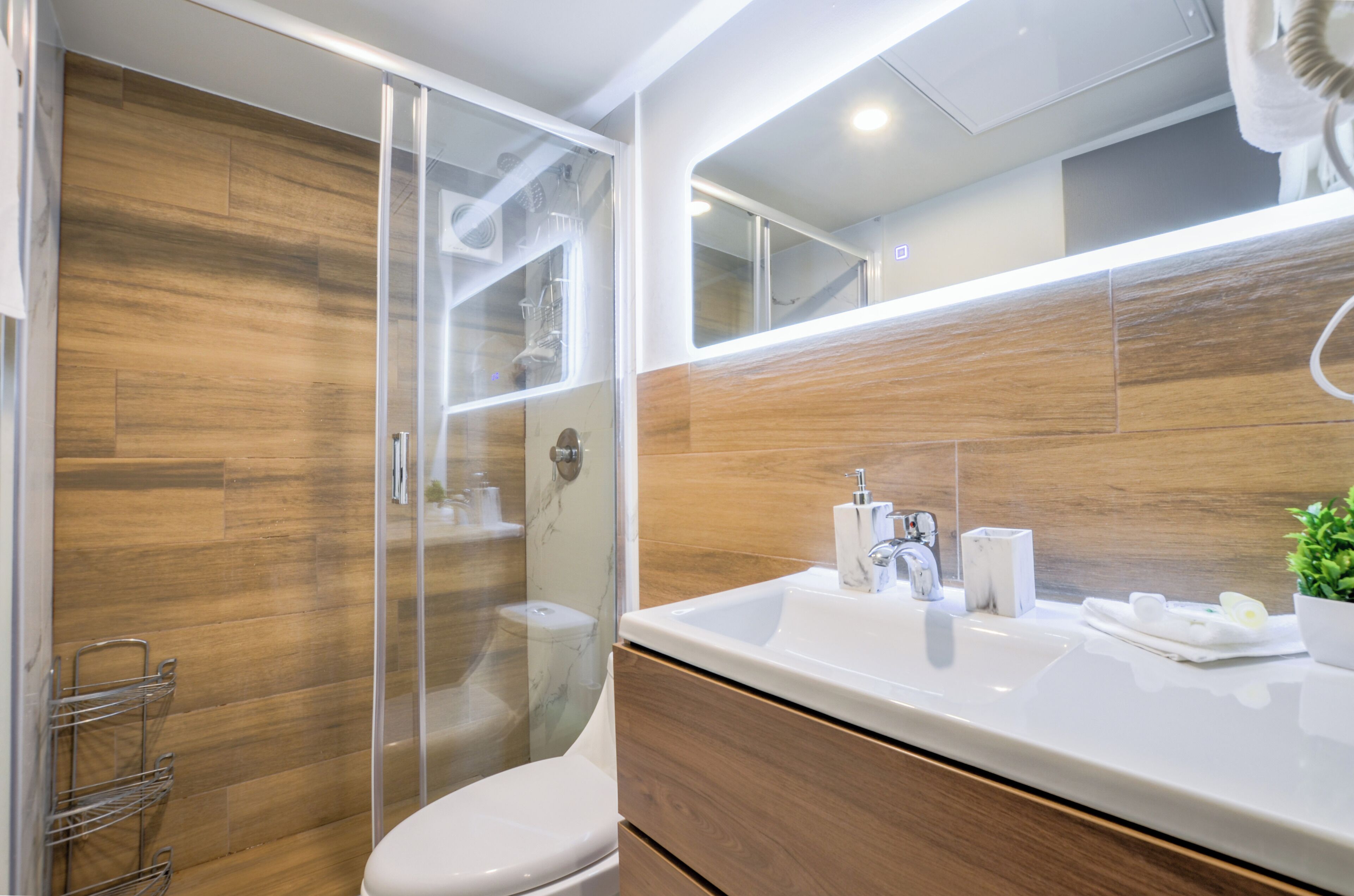 Une salle de bain moderne avec un meuble-lavabo en bois, une cabine de douche en verre et un grand miroir.