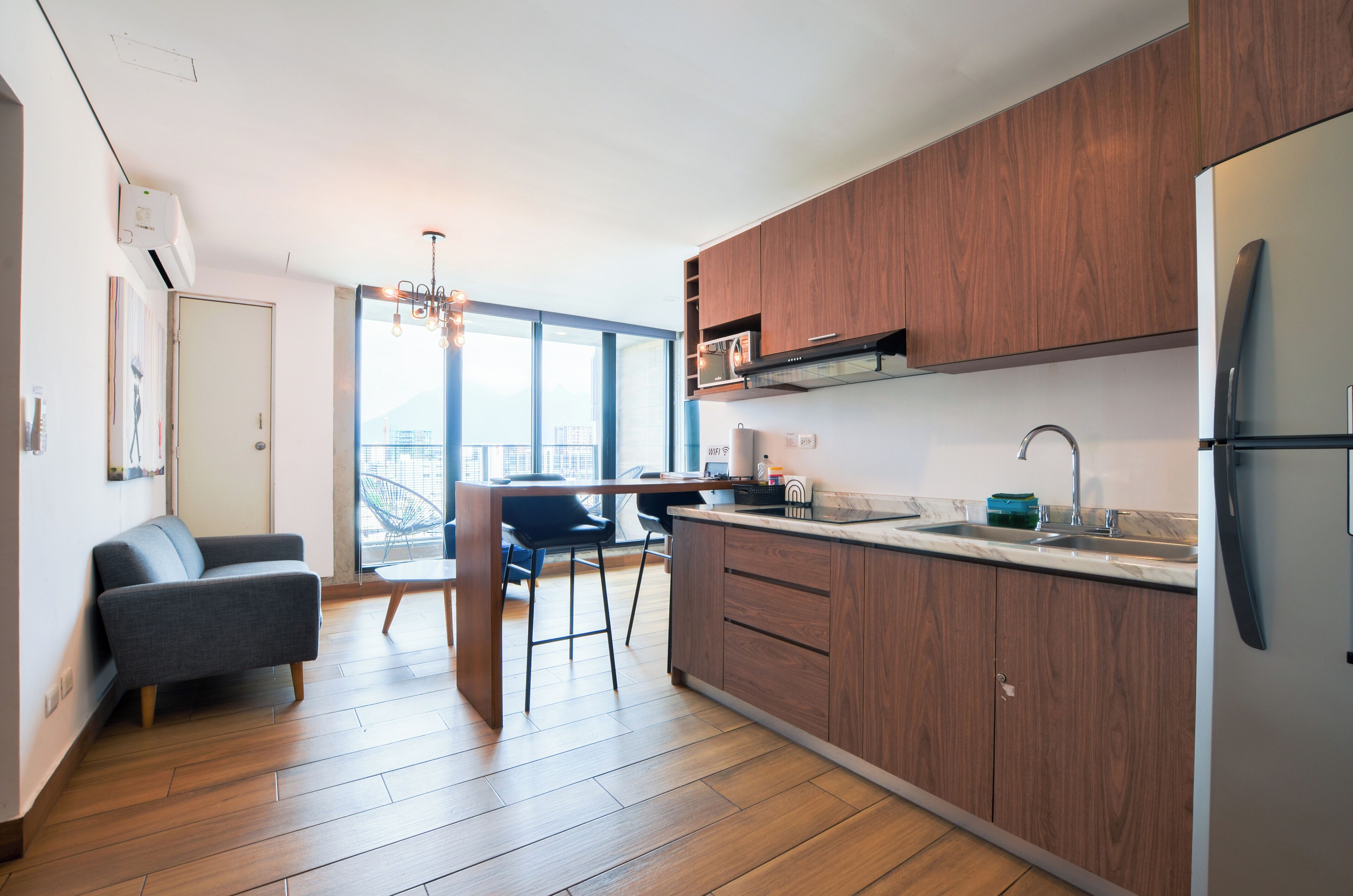 A modern kitchen with wooden cabinets, a built-in oven, and a stainless steel refrigerator.