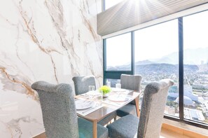 Zona pranzo con parete in marmo, ampia finestra vista città e tavolo apparecchiato per quattro persone.