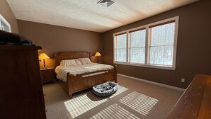 A bedroom with a bed, bedside lamps, a window, and a carpeted floor. - Tremendous 5-bedroom house in Pocono Pines (Pocono Pines)