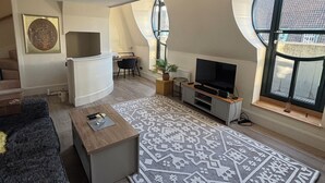 A modern living room with a large TV, a sofa, a coffee table, and a patterned rug. - Two bedroom two bathroom whole apartment in Westminster (London)