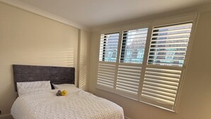 A bedroom with a bed, wooden flooring, and a window with blinds. - Two bedroom two bathroom whole apartment in Westminster (London)