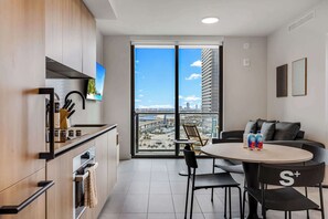 A modern kitchen with a large window, a dining area with a round table, and a sofa. - High-Rise Miami Condo | Rooftop Pool | Sea View (Miami)
