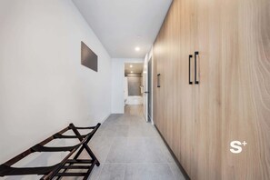 A modern hallway with a wooden wardrobe, a bench, and a door leading to a bathroom. - High-Rise Miami Condo | Rooftop Pool | Sea View (Miami)